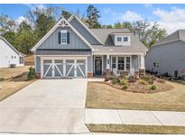 Charming blue home featuring a two-car garage, inviting front porch and manicured lawn at 221 Hickory Bluffs Pkwy, Canton, GA 30114