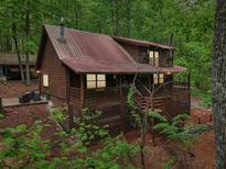 Charming log cabin nestled in a wooded setting with a metal roof and inviting front porch at 2361 Mann Rd, Douglasville, GA 30134