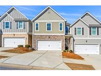 Charming townhouse with brick accents, white garage door, and well-maintained landscaping on a sunny day at 7492 Knoll Hollow Rd, Lithonia, GA 30058