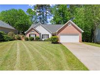 Charming single-story home featuring a brick facade, two-car garage, and a well-manicured lawn with mature trees at 2880 Cressington Nw Bnd, Kennesaw, GA 30144
