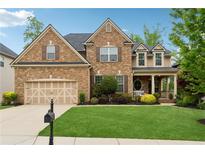 Charming brick home with a well-manicured lawn, two car garage, and inviting front porch at 280 Lakestone Pkwy, Woodstock, GA 30188