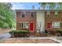 Charming brick townhome with well-manicured landscaping and vibrant red doors at 450 High Creek Trce, Roswell, GA 30076