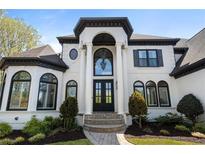Stunning white and black two-story home with an elegant entryway and manicured landscaping at 1015 Bedford Gardens Dr, Alpharetta, GA 30022