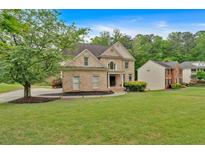 Charming brick home featuring a well-manicured lawn and mature trees in a serene, suburban setting at 2480 Ashbourne Dr, Lawrenceville, GA 30043