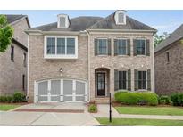 Charming two-story brick home with a well-manicured lawn and attached two-car garage at 6265 Bellmoore Park Ln, Johns Creek, GA 30097