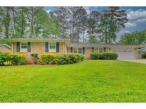 Charming brick home with well-manicured lawn and mature landscaping with blue shutters at 4507 N Peachtree Rd, Dunwoody, GA 30338