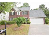 Charming two-story red brick home with a two-car garage and a well-manicured lawn at 1120 Lake Lucerne Rd, Lilburn, GA 30047