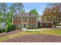 Stately two-story brick home featuring gray shutters, dormer windows, and lush landscaping at 230 Seamarsh Ct, Atlanta, GA 30328