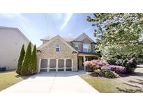 Charming two-story home featuring a brick facade, attached two-car garage, and beautifully landscaped front yard at 881 Upland Ives Dr, Sugar Hill, GA 30518