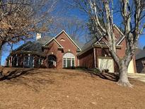 Charming red brick home featuring a well-manicured lawn and attached two-car garage at 378 Rhodes House Dr, Suwanee, GA 30024