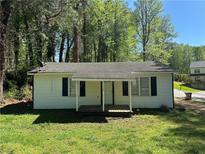 Charming single-story home featuring a cozy front porch and well-maintained lawn at 128 13Th St, Cumming, GA 30040