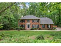 Charming brick home featuring a well-manicured front yard and mature trees at 1440 Sandford Sw Trl, Lilburn, GA 30047