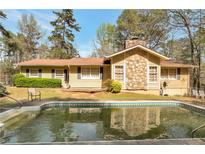 Ranch style house with stone chimney and in-ground pool at 2004 Poplar Falls Rd, Lithonia, GA 30058