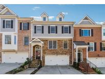 Charming three-story townhome with stone facade, arched entryway, and attached two-car garage at 1236 Brickton Nw Dr, Atlanta, GA 30318
