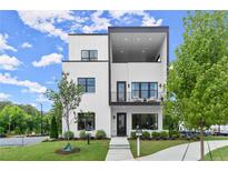 Modern two-story home featuring white brick, black trim, a covered balcony and a well-manicured lawn at 326 Treble Way, Alpharetta, GA 30009