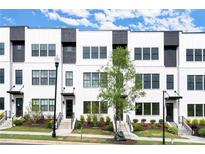 Modern townhome exterior features white brick, black window frames, and professionally landscaped front yard at 673 Soul Aly # 146, Alpharetta, GA 30009