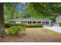 Charming brick home with a covered porch and landscaped front yard featuring mature trees and manicured bushes at 3501 Montreal Way, Tucker, GA 30084
