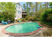 Backyard pool with a red-brick border offers a private, relaxing outdoor space with ample lounge seating at 225 Nacoochee Dr, Woodstock, GA 30188