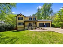 Charming yellow two-story home featuring a well-manicured lawn, an attached two-car garage, and mature trees at 664 Somerset Dr, Lawrenceville, GA 30046