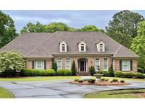 Elegant brick home featuring manicured landscaping, a circular driveway, and a charming water fountain at 1551 Pharrs Rd., Snellville, GA 30078