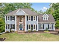 Beautiful traditional home with a manicured lawn, blue paint, and a striking stone accent around the front entrance at 1039 Avery Creek Dr, Woodstock, GA 30188