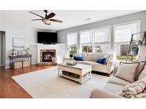 Bright living room with a cozy fireplace, ceiling fan, and plush furniture at 233 Hampton Station Blvd, Canton, GA 30115