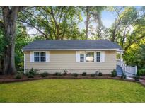Charming single-story home with light yellow siding, white-framed windows, and well-manicured landscaping at 1900 Meadow Ln, Decatur, GA 30032