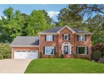 Charming two-story brick home with a well-manicured lawn and attached two car garage at 431 Shore Dr, Suwanee, GA 30024
