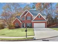 Charming two-story brick home features a well-manicured lawn, two-car garage, and mature trees at 893 Brookgreen Pl, Lawrenceville, GA 30043