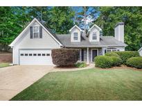 Charming traditional home with a well-manicured lawn, attached garage, and mature trees at 5410 Lenox Park Pl, Buford, GA 30518