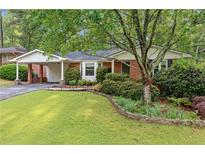 Charming brick home with a well-maintained lawn, lush landscaping and a convenient carport at 1866 Wildwood Ne Pl, Atlanta, GA 30324