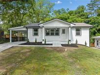 Charming white brick home featuring a carport, black trim, and a manicured front yard at 130 Oakcliff Court, Atlanta, GA 30331
