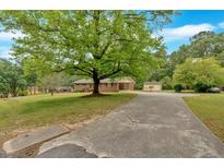 Charming brick home featuring a spacious front yard with a large, mature tree and a long driveway at 115 Pine Tree Dr, Fayetteville, GA 30214