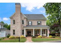 Charming brick two-story home with a covered front porch, columns, and a professionally landscaped yard at 215 Scott Xing, Roswell, GA 30076