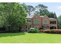 Charming brick home with stone accents, arched porch, lush landscaping, and mature trees on a well-manicured lawn at 4835 Merlendale Ct, Atlanta, GA 30327