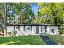 Charming home featuring a white painted brick exterior, black shutters, and a well-manicured lawn surrounded by mature trees at 2905 Gresham Se Rd, Atlanta, GA 30316