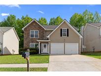Charming two-story home featuring a stone facade, two-car garage, and well-maintained front yard at 4087 Rosebud Park Dr, Snellville, GA 30039