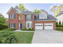 Charming brick home with a well-manicured lawn, two-car garage, and classic architectural details at 3145 Maple Terrace Drive, Suwanee, GA 30024