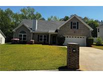 Charming brick home with a well-manicured lawn, driveway, and colorful flowerbeds at 20 Chapman Way, Covington, GA 30016