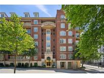 Beautiful brick building with ornate balconies and lush green trees surrounding the exterior at 77 Peachtree Ne Pl # 107, Atlanta, GA 30309