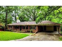 Charming brick ranch-style home with a covered carport and cozy front porch surrounded by mature trees at 6470 Sherwood Trl, Austell, GA 30168