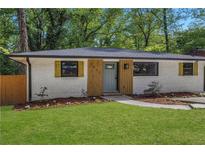 Charming white brick home with modern wood accents, green lawn, and lush landscaping at 2392 Jefferson Ter, Atlanta, GA 30344