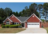 Charming red brick home with manicured landscaping, an attached garage, and a classic architectural design at 310 Morning Glen Dr, Suwanee, GA 30024