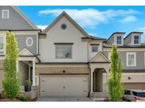 Charming townhouse with neutral siding, brick accents, a two-car garage, and manicured landscaping at 409 Retreat Ln, Canton, GA 30114