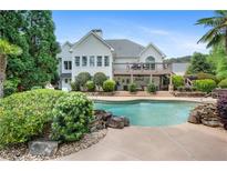 Tranquil backyard with a sparkling pool, mature landscaping, a deck, and a stone retaining wall at 109 Hawks Bnd, Canton, GA 30115