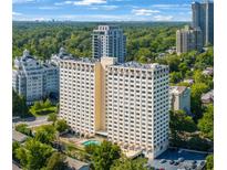 Stunning view of the high-rise condo building showing the pool, parking, and mature trees at 2479 Peachtree Ne St # 1414, Atlanta, GA 30305