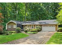 Charming ranch home with brick accents, lush landscaping, and a brick driveway, surrounded by mature trees at 4293 Smithsonia Dr, Tucker, GA 30084