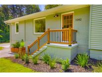 Charming front porch with wooden railing, nicely landscaped yard, and natural wood door at 1042 Oakdale Se Dr, Smyrna, GA 30080