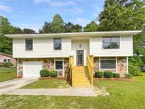 Charming two-story home with stone accents, new stairs, a manicured lawn and mature trees at 6735 Smoke Ridge Dr, Atlanta, GA 30349