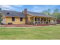 Inviting yellow home with a covered porch, lush lawn, and mature trees at 255 Deer Run Rd, Ellenwood, GA 30294